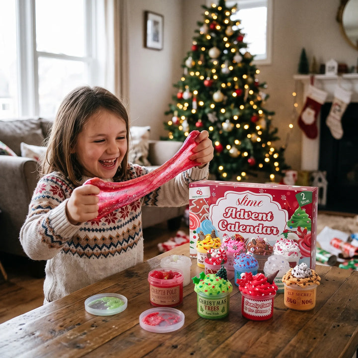 Fillette souriante étirant du slime rouge pailleté devant un sapin de Noël, avec la boîte du calendrier et les pots ouverts 1