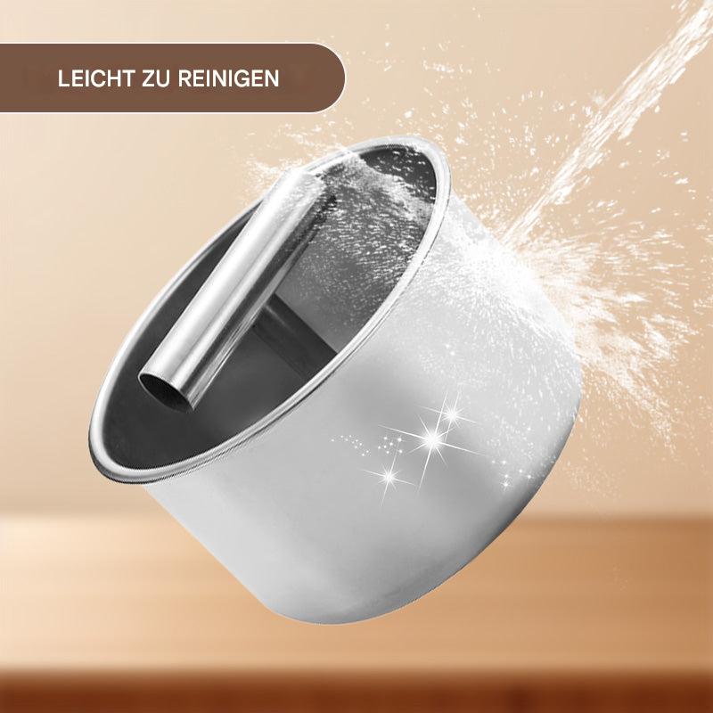 Récipient en acier inoxydable et sa poignée rincés sous un jet d'eau, avec des éclats brillants illustrant la facilité de nettoyage. 6