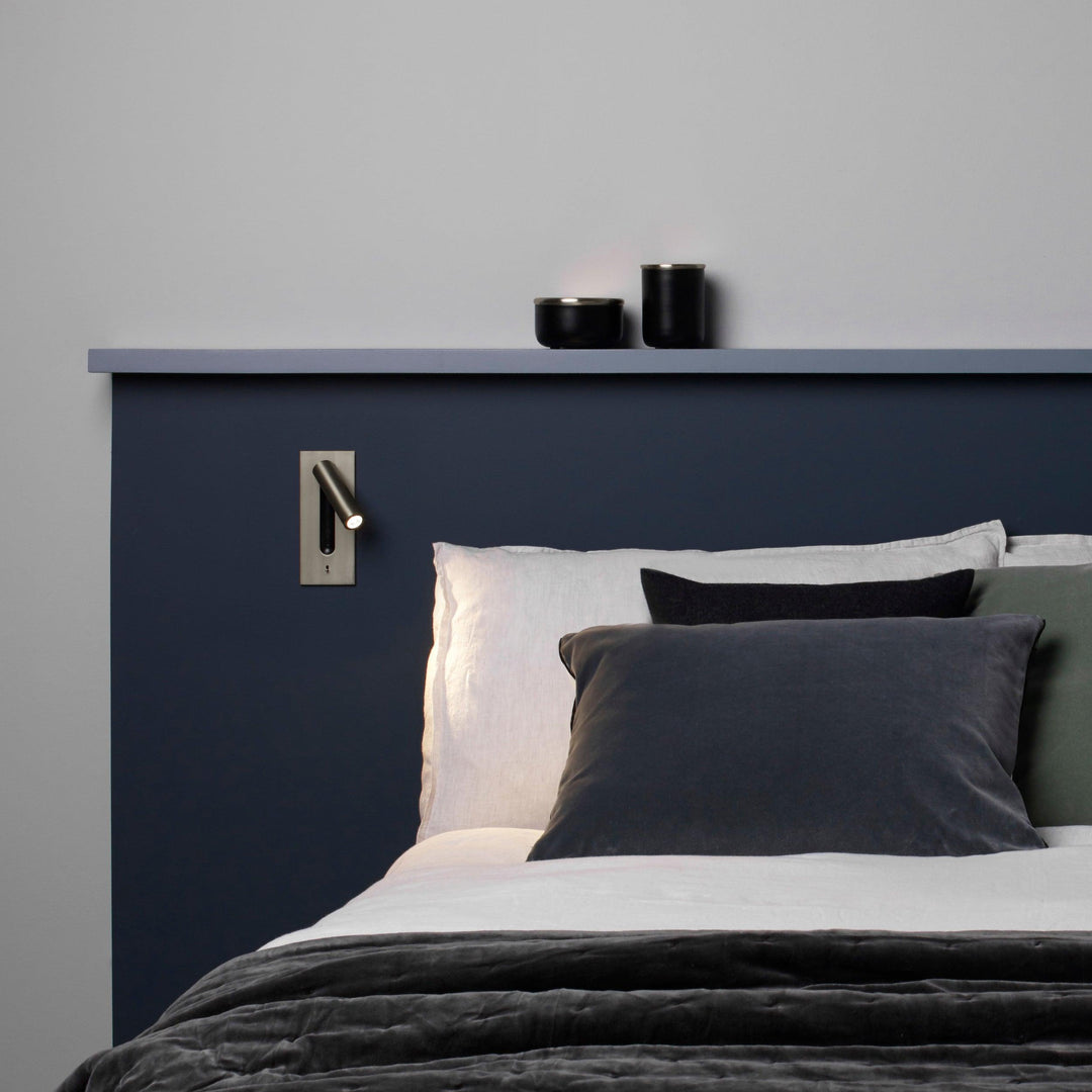 Applique bronze au-dessus d'un lit à tête de lit bleu marine, oreillers gris 30
