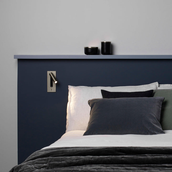 Applique bronze au-dessus d'un lit à tête de lit bleu marine, oreillers gris 30