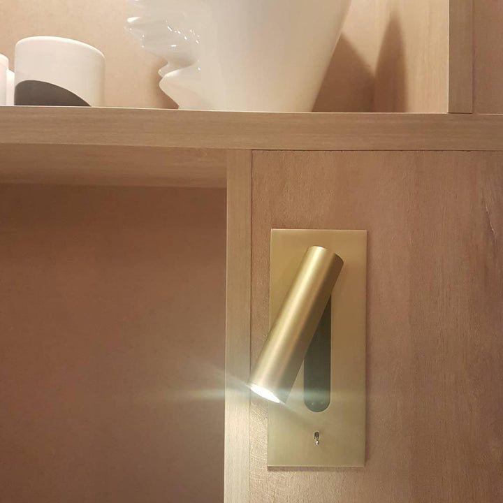 Applique dorée encastrée dans un meuble en bois clair, spot allumé près d'une étagère 32