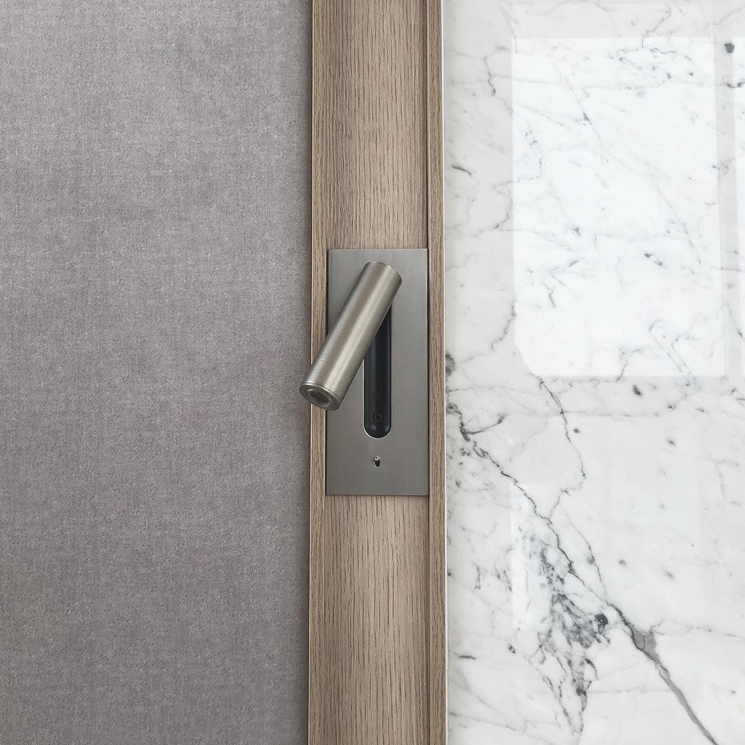 Applique en métal brossé, spot tourné vers la gauche, entre un mur en tissu gris et du marbre 33