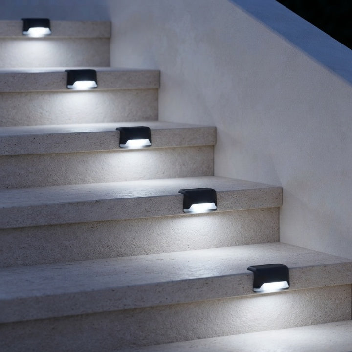 Lampes solaires noires sur un escalier clair le long d'un mur, diffusant une lumière blanc froid vers chaque marche. 5