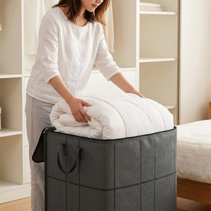 Femme glissant une couette blanche pliée dans le sac gris ouvert, devant une étagère de rangement. 3