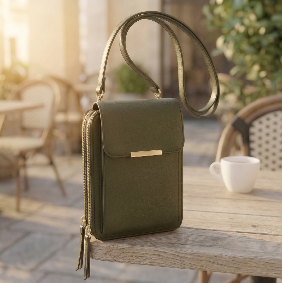 Version vert olive du sac à bandoulière, vue de trois quarts sur une table en bois avec une tasse blanche. 5