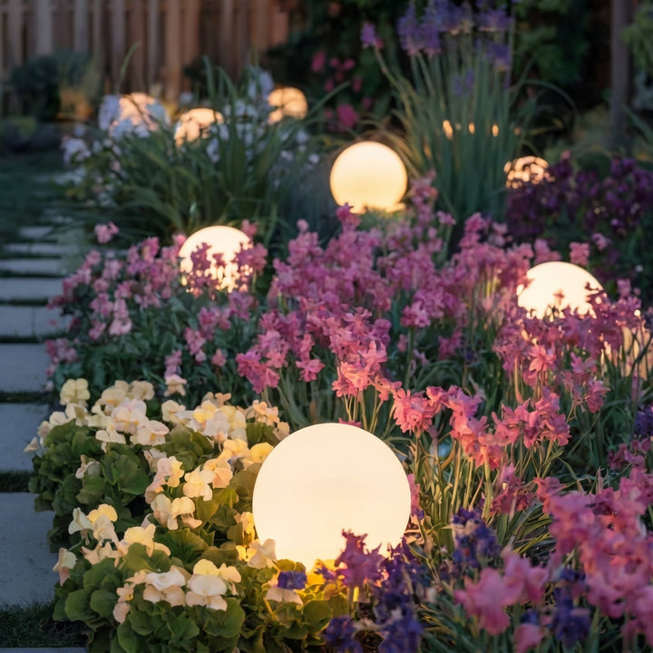 Sphères lumineuses à la lueur chaude, disséminées dans un massif dense de fleurs roses, violettes et crème au crépuscule. 7