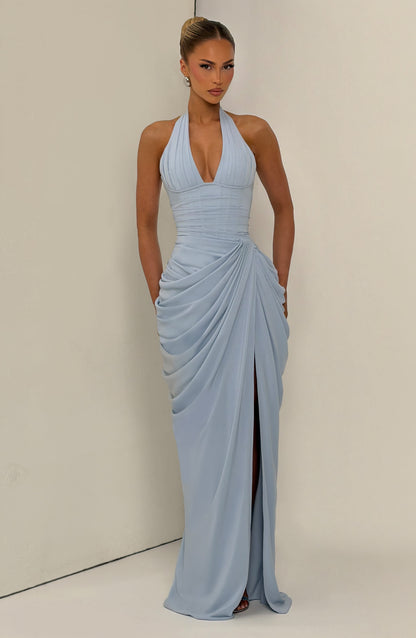 Robe bleu clair portée de face dans un décor beige, jupe drapée et fente centrale sur la jambe. 15