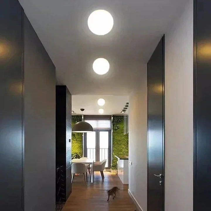 Deux sphères lumineuses au plafond d'un long couloir sombre menant à une salle à manger 1