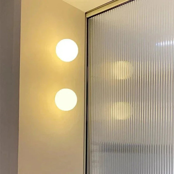 Deux sphères lumineuses superposées sur un mur, à côté d'une cloison en verre cannelé 14