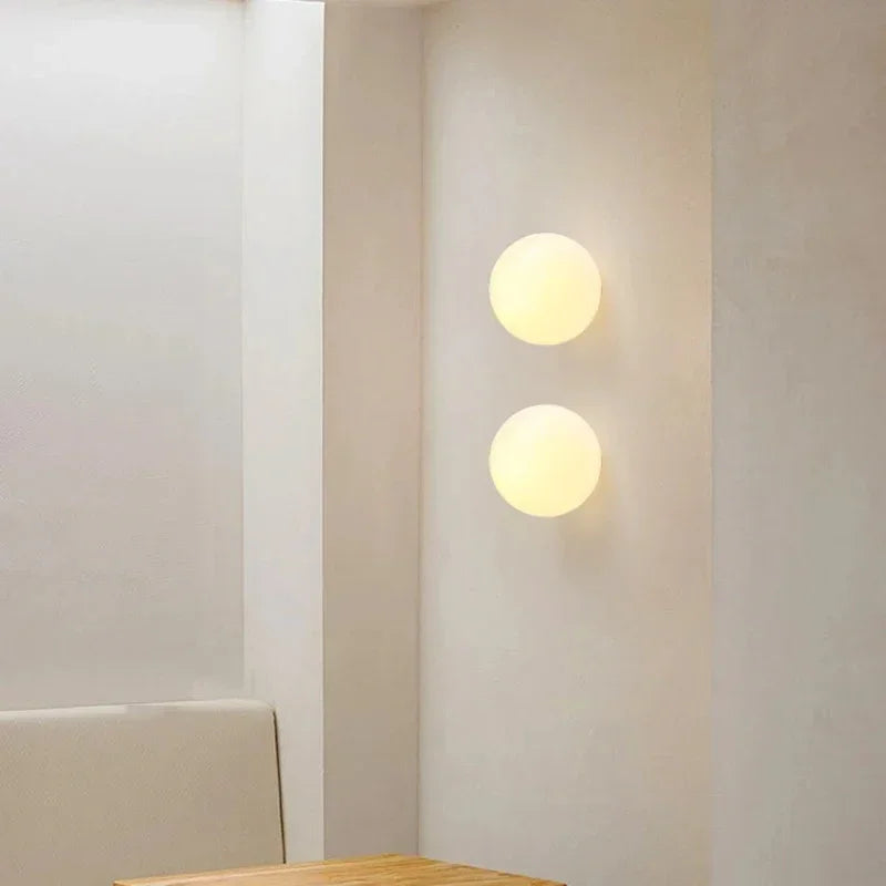 Deux appliques sphériques en verre opale alignées verticalement sur un mur clair 15
