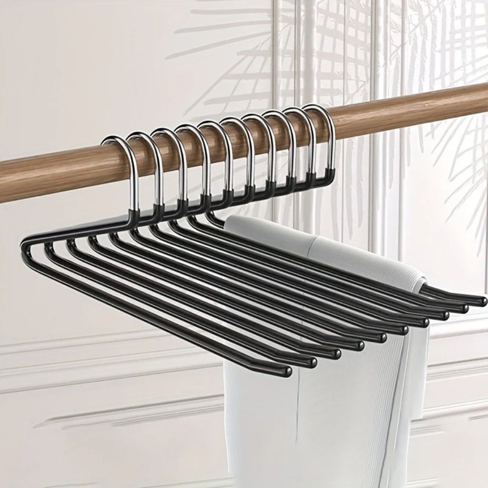 Série de cintres noirs accrochés à une tringle en bois, avec un pantalon blanc suspendu 1