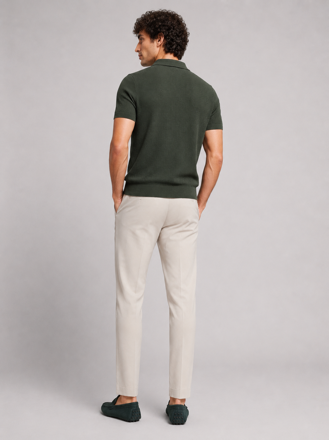 Polo vert foncé vu de dos, homme tourné de côté, pantalon beige et mocassins 14