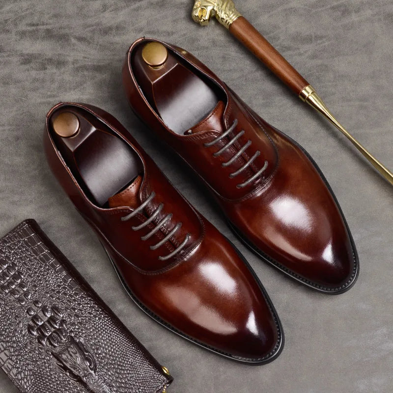 Paire d'Oxford bordeaux à lacets vue du dessus avec embauchoirs, posée près d'une pochette en cuir croco 4