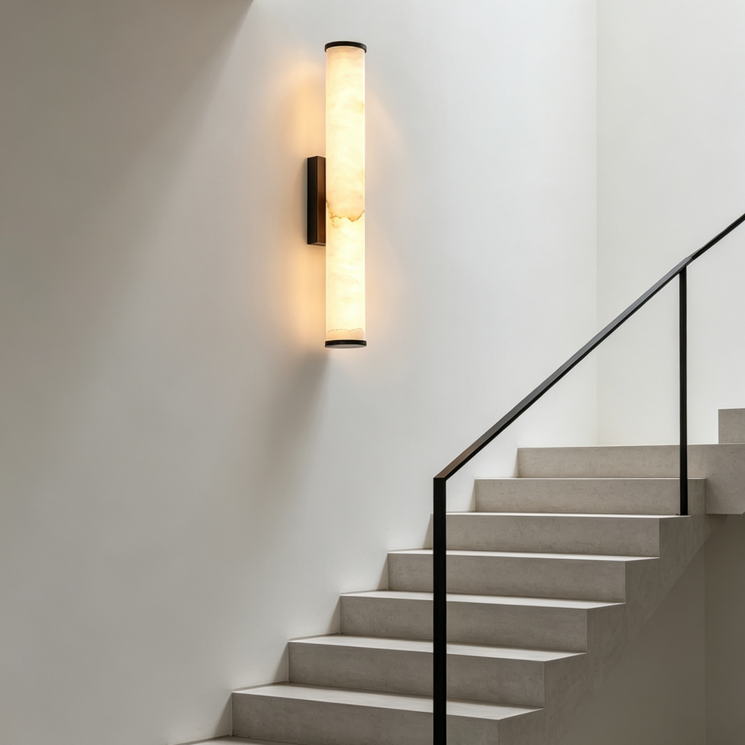 Applique cylindrique allumée sur un mur blanc au-dessus d'un escalier en pierre claire à rampe noire. 7