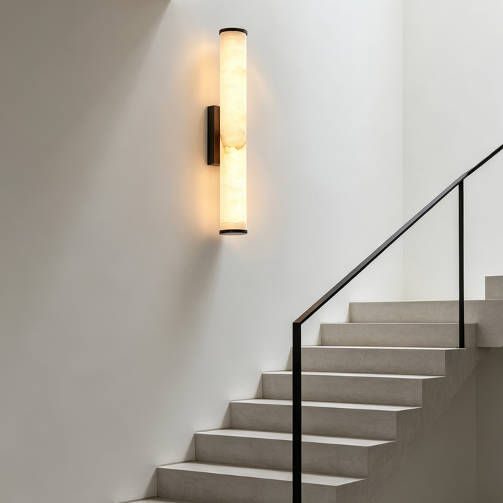 Applique cylindrique allumée sur un mur blanc au-dessus d'un escalier en pierre claire à rampe noire. 7