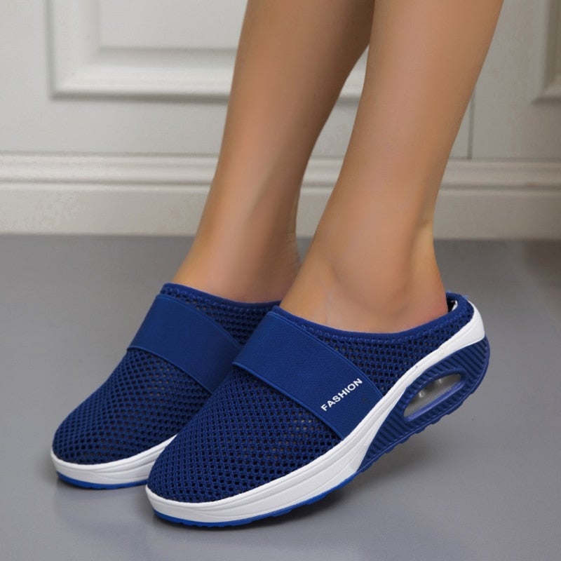 Paire de mules bleu marine en maille portées, vue de face sur sol gris, coussin d'air visible 5