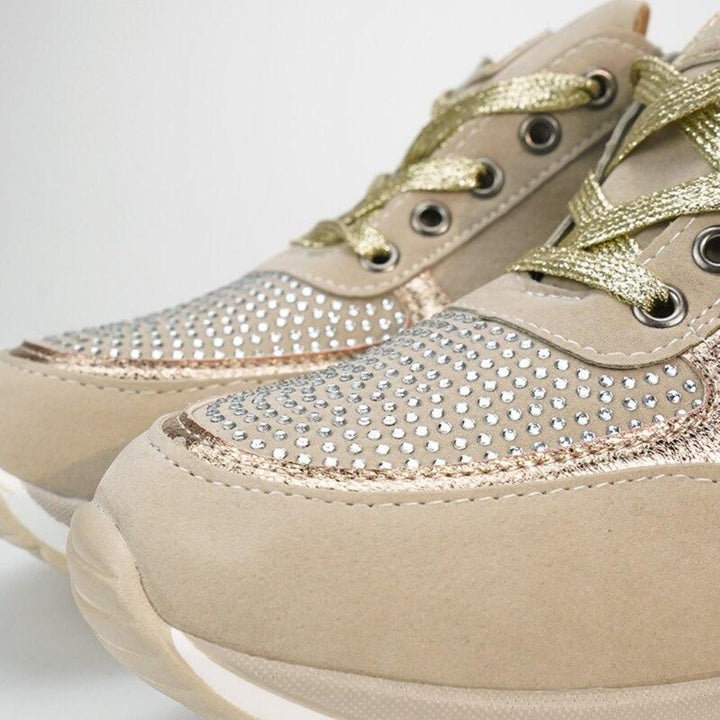 Gros plan sur le bout d'une paire de baskets beiges avec strass, liserés dorés et lacets métallisés. 10