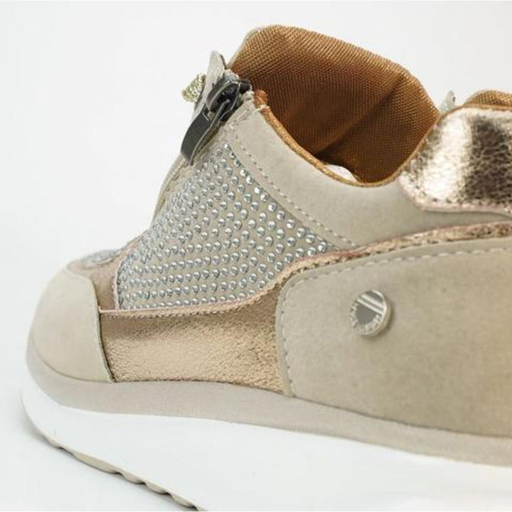 Gros plan sur le talon et le zip latéral d'une basket beige, avec strass, empiècement métallisé et doublure intérieure orangée. 9