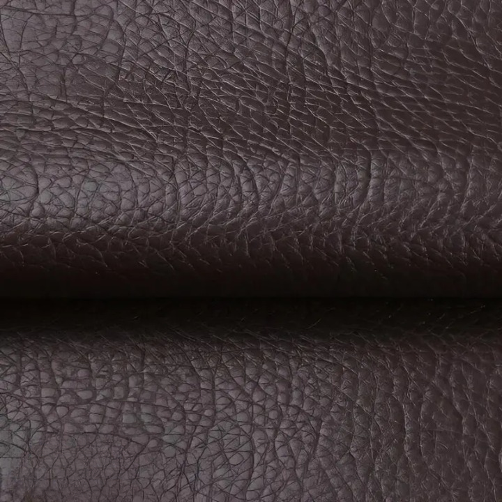 Gros plan sur la texture grainée du cuir synthétique brun foncé, plié au milieu 9