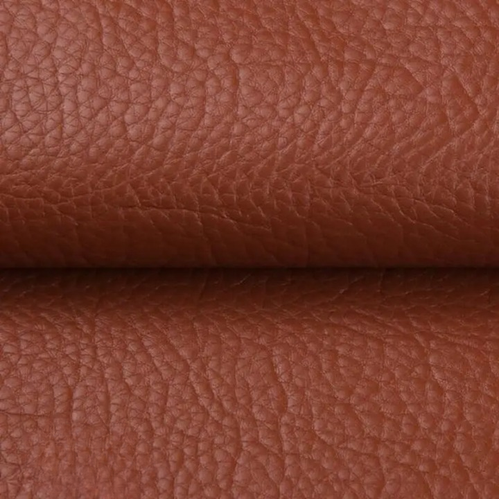 Gros plan sur la texture grainée du cuir synthétique brun roux, plié au milieu 12