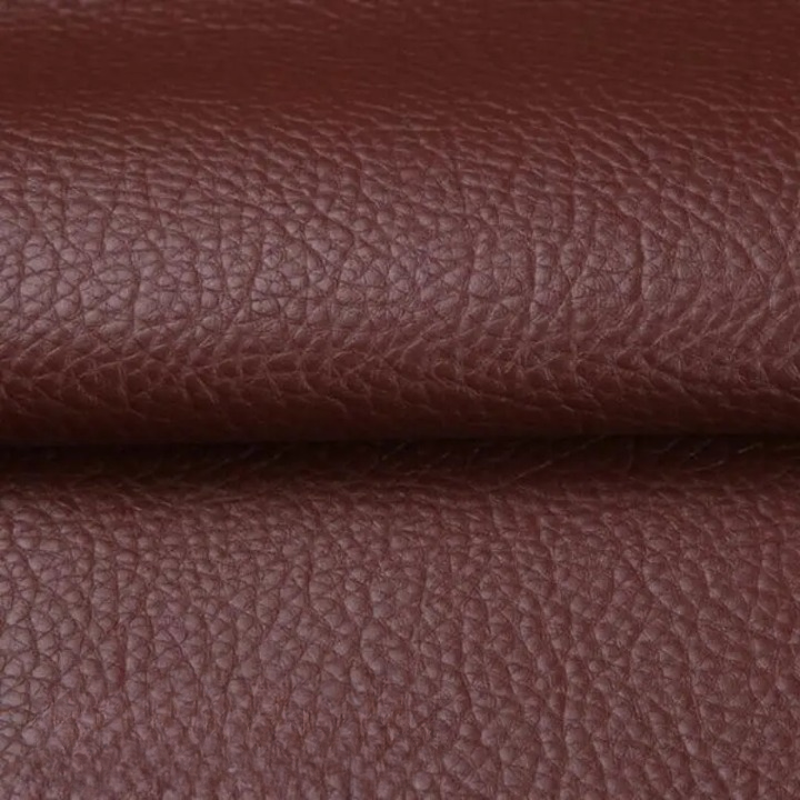 Gros plan sur la texture grainée du cuir synthétique brun bordeaux, plié au milieu 13