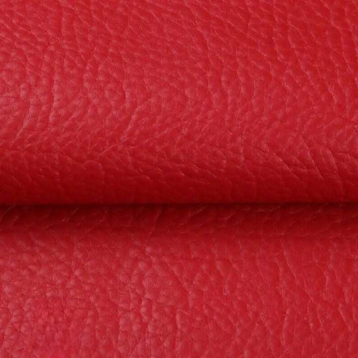 Gros plan sur la texture grainée du cuir synthétique rouge vif, plié au milieu 14