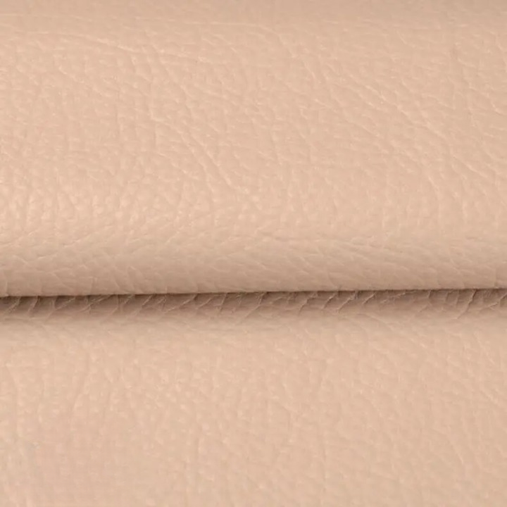 Gros plan sur la texture grainée du cuir synthétique beige rosé, plié au milieu 15