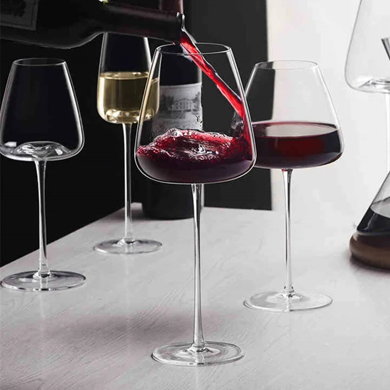 Vin rouge versé depuis une bouteille dans un verre, avec d'autres verres et un carafe en arrière-plan 2