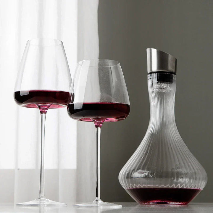 Deux verres à pied remplis de vin rouge à côté d'une carafe cannelée avec bouchon métallique 3