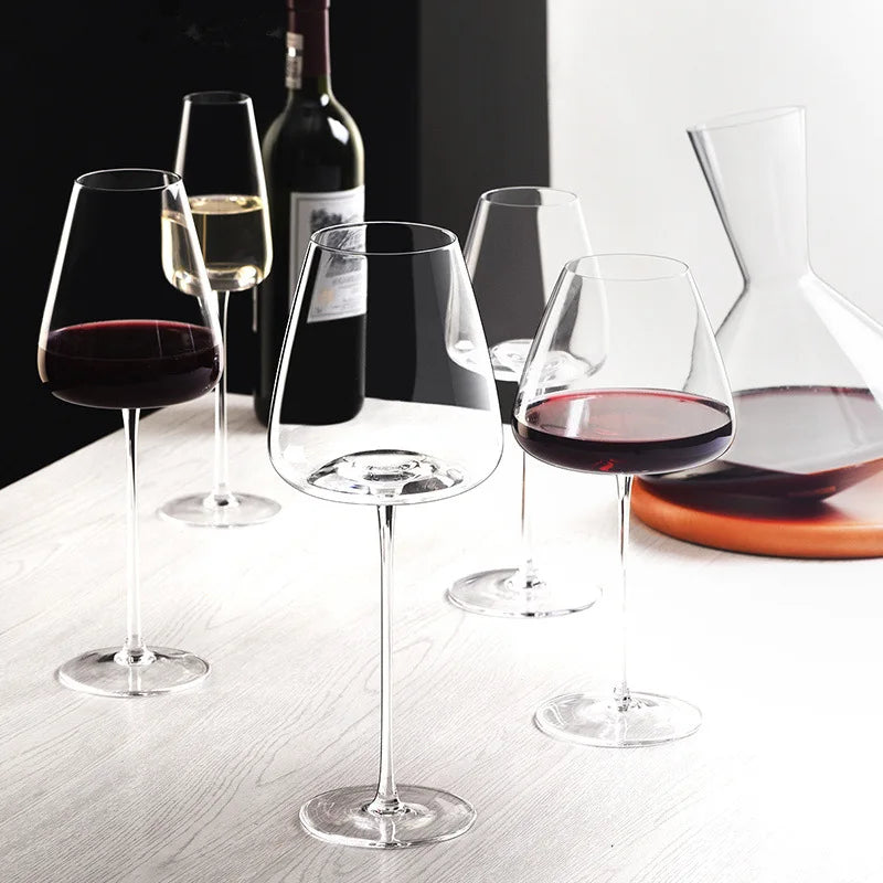 Verres de vin rouge, flûte et bouteille sur une table claire, avec une carafe sur plateau en bois 6