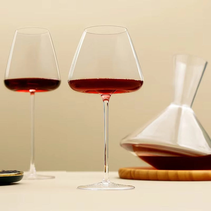 Deux verres à vin rouge sur fond beige, avec une carafe posée sur un plateau en bois 8