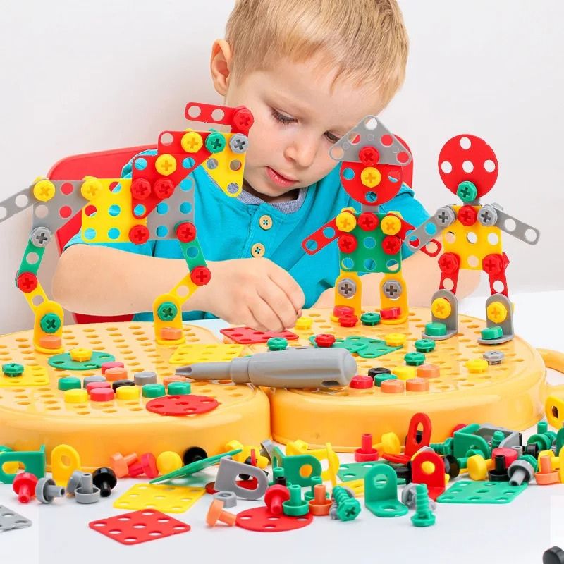Enfant concentré construisant plusieurs figurines de robots avec des plaques, vis et écrous colorés fixés sur la plaque de jeu jaune. 2