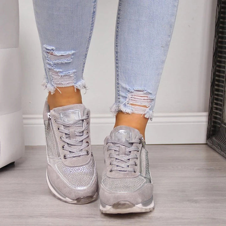 Vue de face de baskets grises à lacets, strass sur l'avant et zip sur le côté, portées avec un jean déchiré. 5