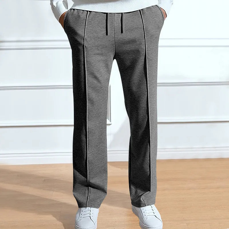 Pantalon gris chiné à taille élastique et plis marqués sur le devant, porté avec un pull blanc et des baskets. 2