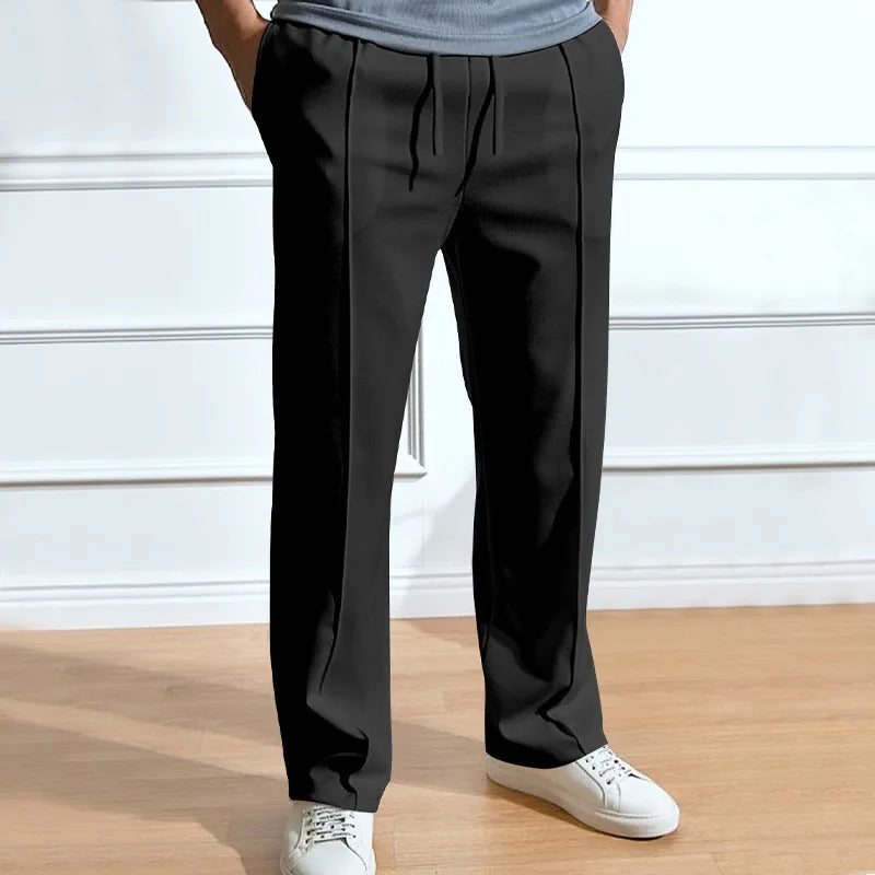 Pantalon noir à taille élastique et cordon, vu de face sur un modèle en t-shirt gris et baskets blanches. 3