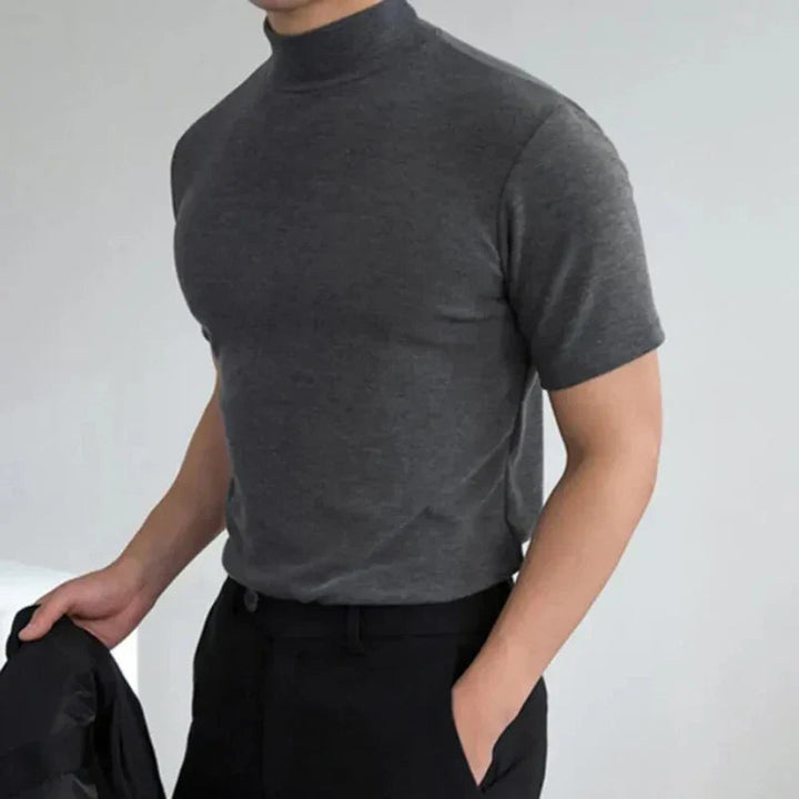 T-shirt gris anthracite à col montant porté par un homme, une main dans la poche d'un pantalon noir. 3