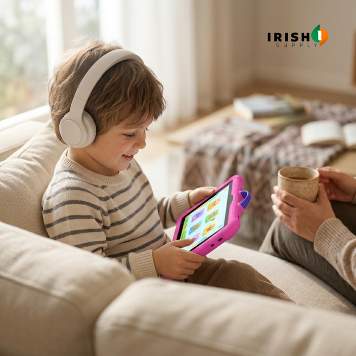 Petit garçon souriant avec un casque audio, assis sur un canapé, joue sur la tablette rose 1