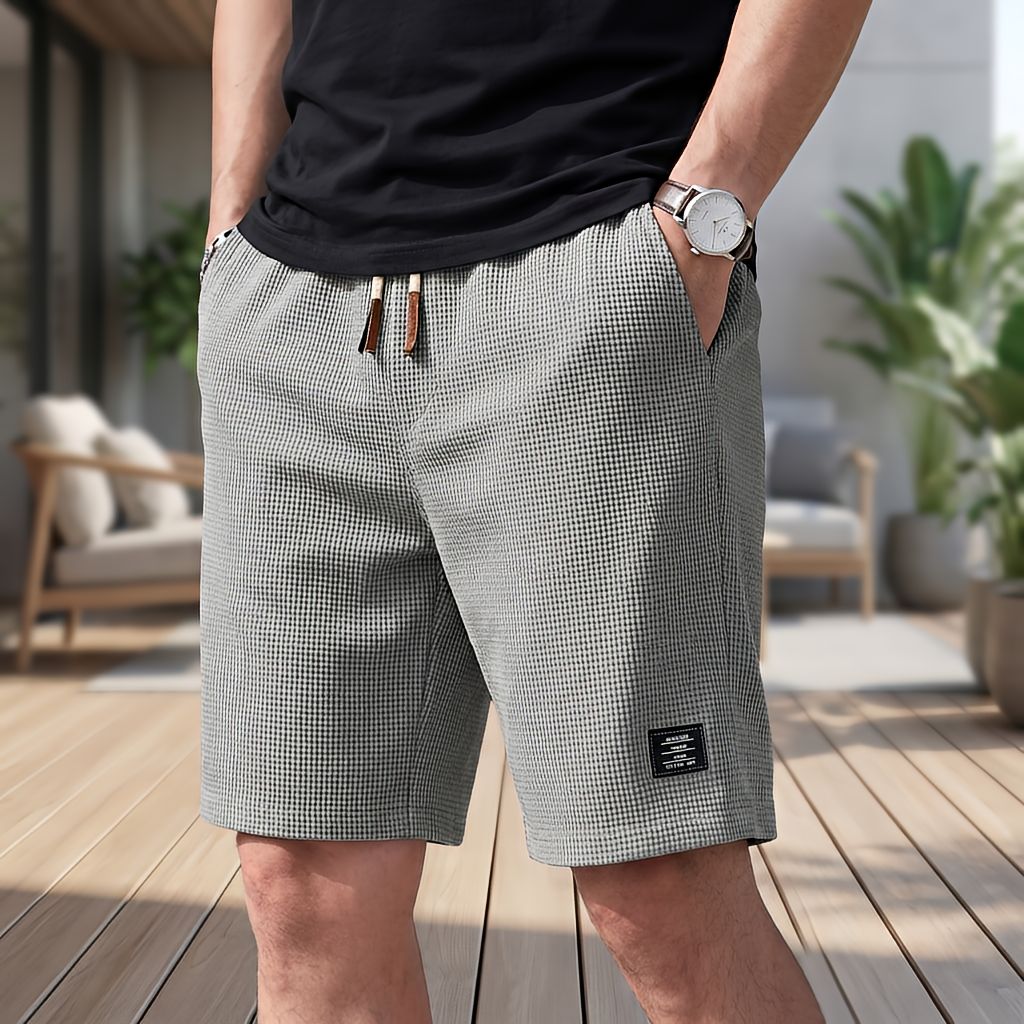 Short gris en tissu gaufré à cordon de serrage, porté avec un tee-shirt noir et une montre, main dans la poche. 6