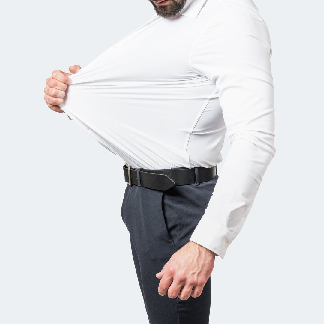 Homme portant une chemise blanche qu'il tire sur le ventre pour montrer son extensibilité, vue de profil 1