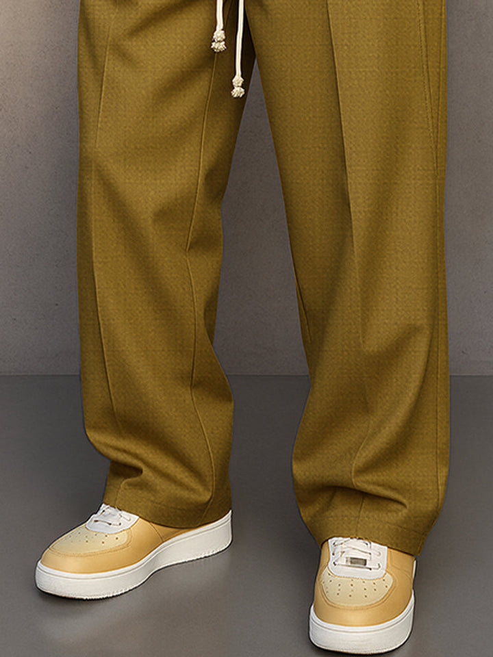 Détail des jambes larges du pantalon vert olive avec plis marqués, porté avec des baskets beiges à semelle blanche. 8
