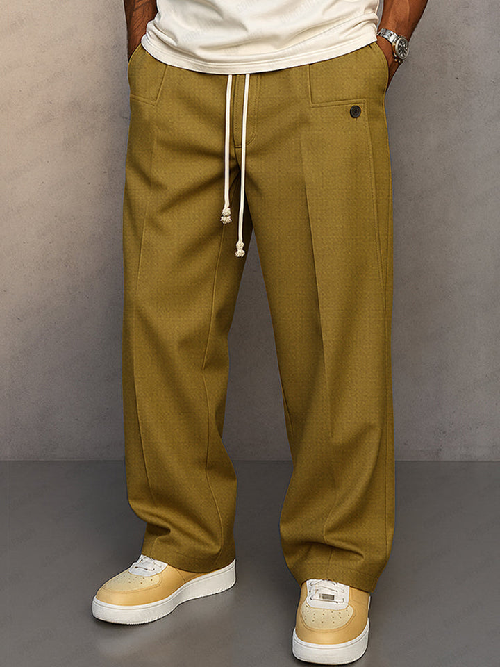 Pantalon ample vert olive porté par un homme, vue de face, cordon de serrage blanc, poches plaquées et baskets beiges. 1