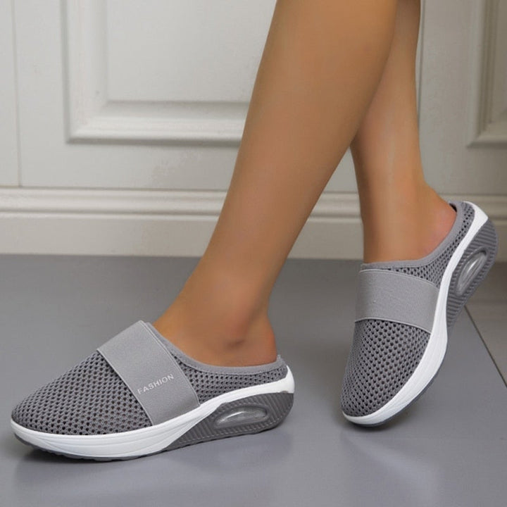 Paire de mules grises en maille portées par une femme, vue de profil sur un sol gris 2