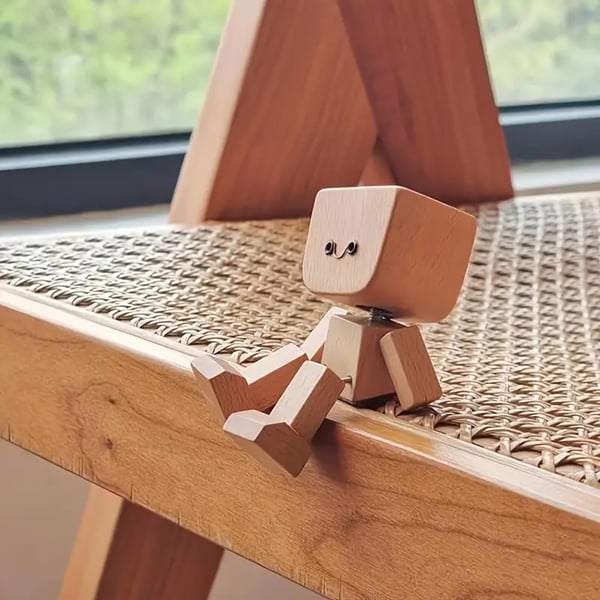 Figurine au visage souriant assise au bord d'une chaise cannée en bois, vue de côté, jambes pendantes. 5