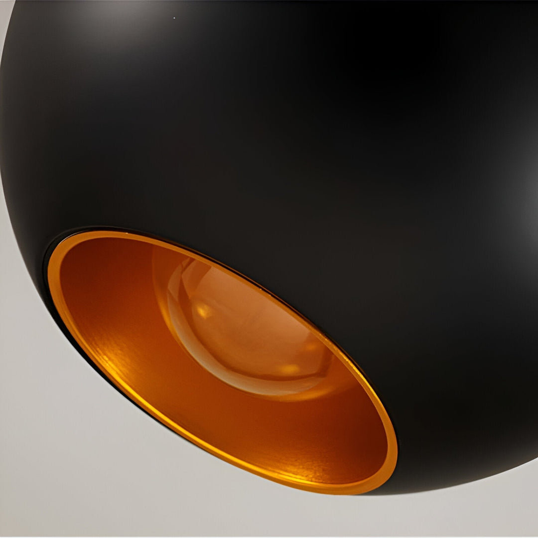 Gros plan sur l'ouverture dorГ©e du bas d'une suspension noire, avec l'ampoule visible Г  l'intГ©rieur. 12