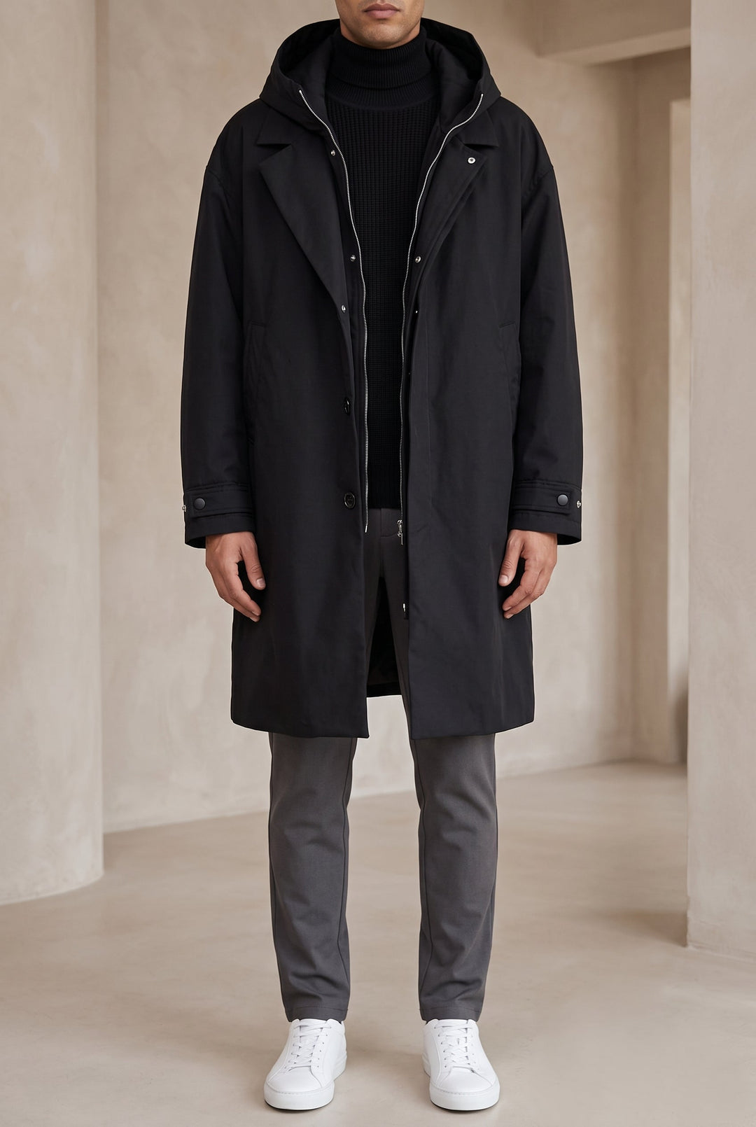 Modèle portant l'imperméable noir en pied, zip ouvert, avec pantalon gris et baskets blanches 6