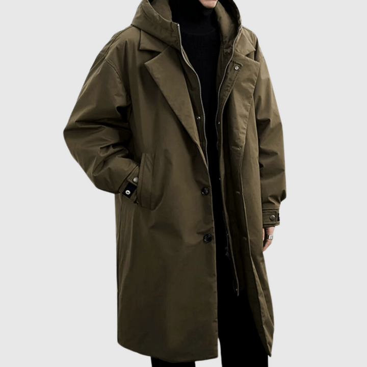 Imperméable vert olive porté par un modèle, vue de face, mains dans les poches, sur fond gris clair 1
