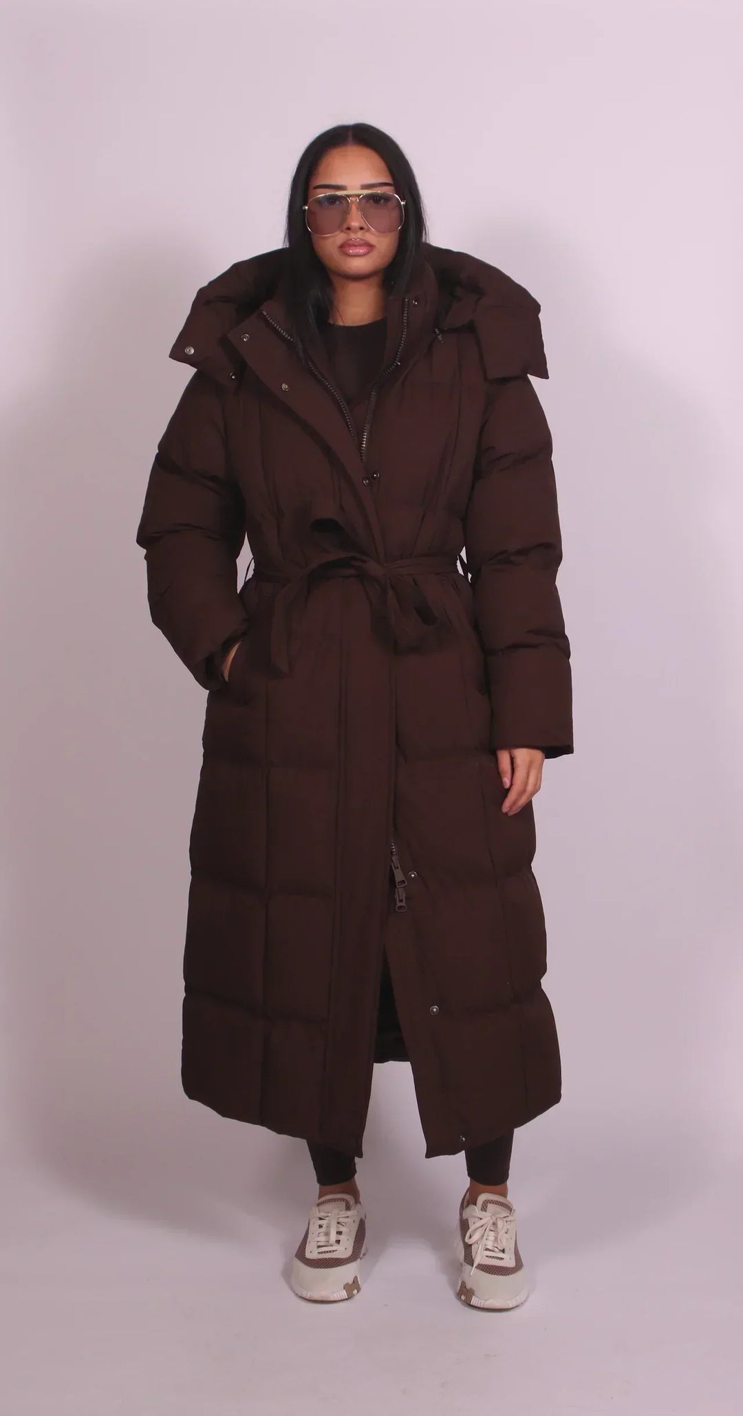 Vue de face de la version marron, portée par une mannequin, ceinture nouée à la taille et capuche relevée 1