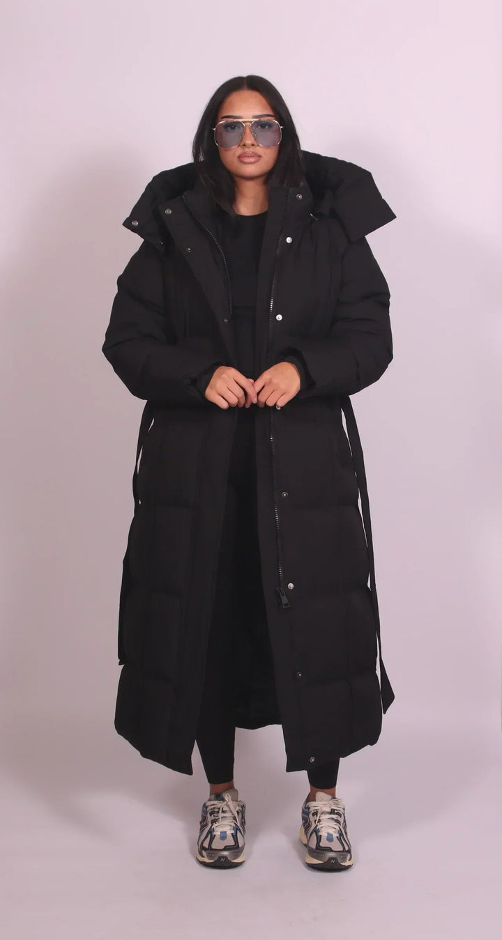 Vue de face de la version noire, portée par une mannequin, zip ouvert et ceinture pendante sur les côtés 2
