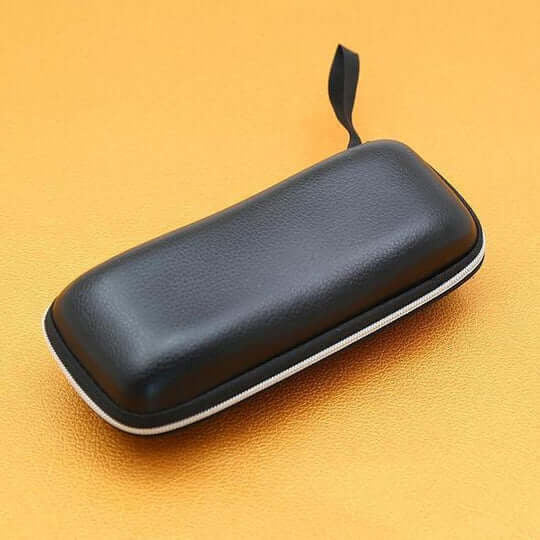 Étui rigide noir à fermeture zippée et petite dragonne, posé sur un fond orangé 11