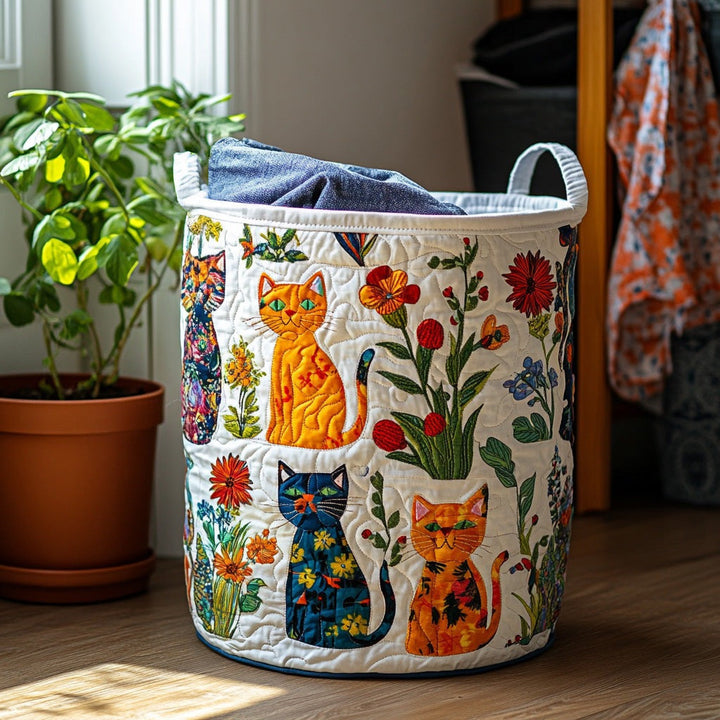 Panier matelassé blanc orné de chats orange et bleus et de fleurs, posé près d'une plante, avec du linge bleu dedans. 1
